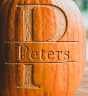 A close crop of the split-letter monogram style, engraved on a pumpkin